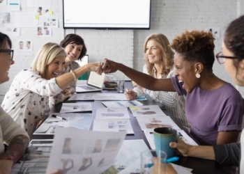 Female designers fist bumping in conference room meeting