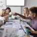 Female designers fist bumping in conference room meeting