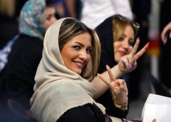 epa05974065 Iranian women flash the victory sign as they wait to cast their ballots in the Iranian presidential elections at a polling station in Tehran, Iran, 19 May 2017.  Out of the group of candidates, the race is tightest between frontrunners Iranian current president Hassan Rouhani and his conservative challenger Ebrahim Raisi.  EPA/ABEDIN TAHERKENAREH