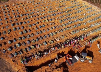 Aerial view of cemetery workers unloading a coffin from a truck at an area where new graves have been dug at the Parque Taruma cemetery, during the COVID-19 coronavirus pandemic in Manaus, Amazonas state, Brazil, on April 21, 2020. - The new area of the cemetery houses graves for suspected and confirmed victims of the COVID-19 coronavirus pandemic. (Photo by MICHAEL DANTAS / AFP)